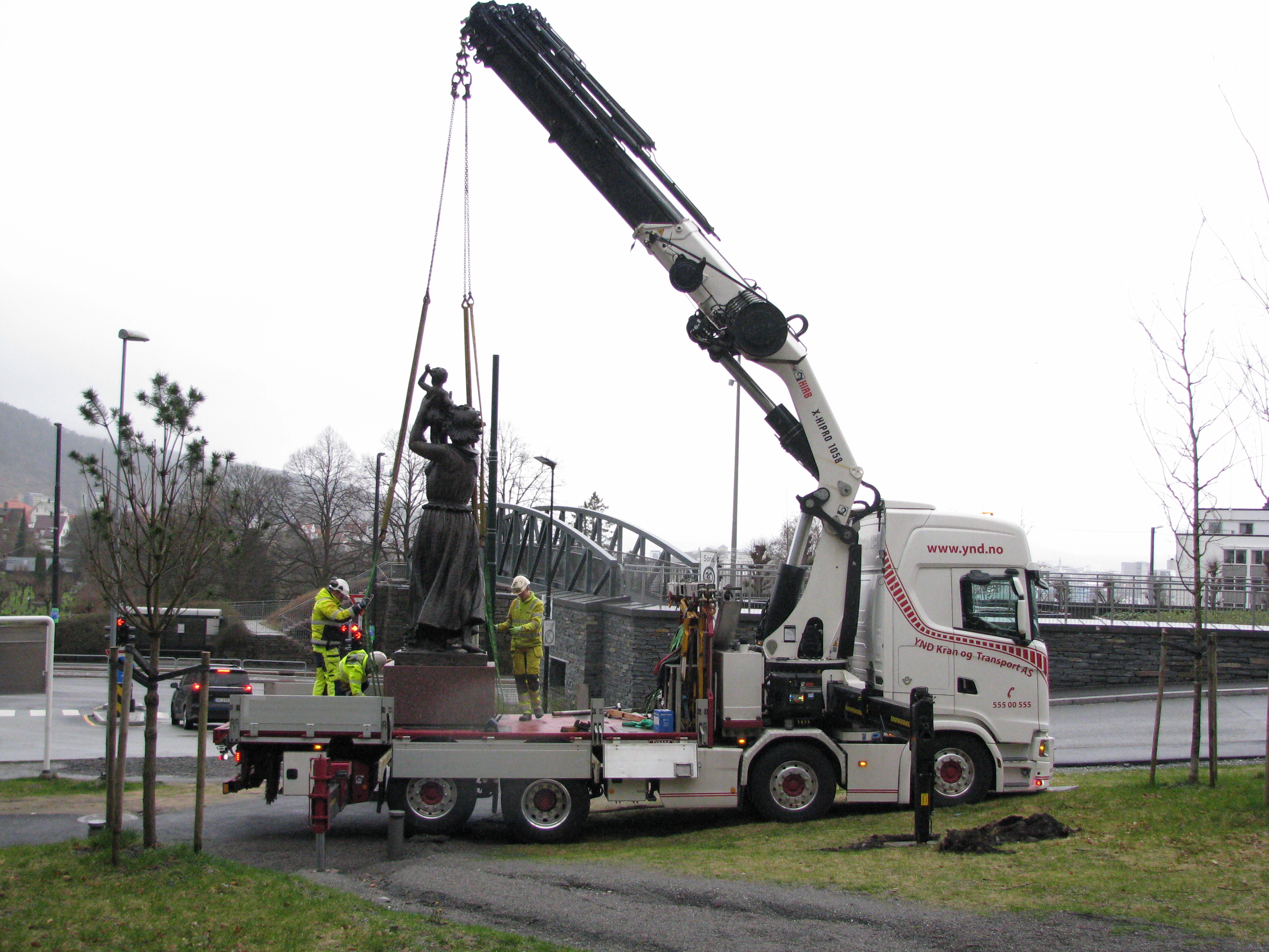 En kran som løfter en statue opp på en lastebil