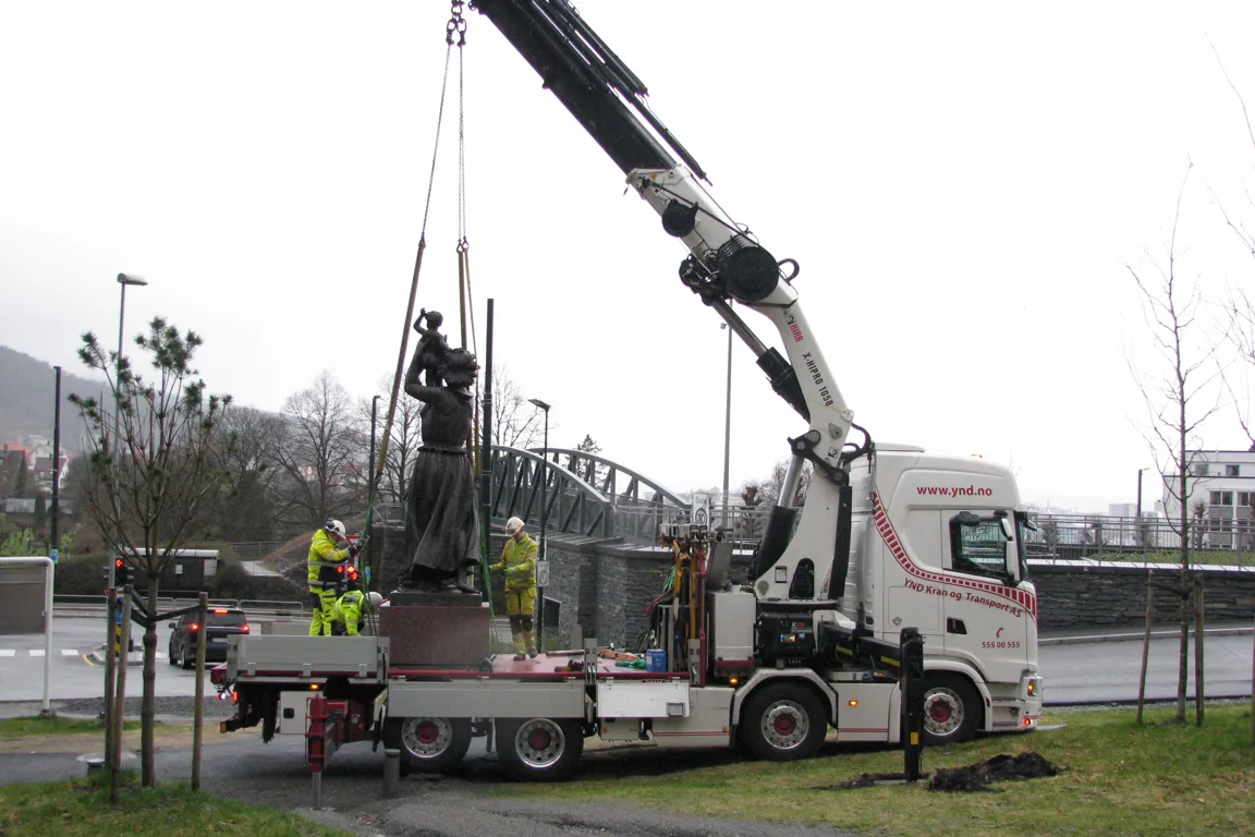 En kran som løfter en statue opp på en lastebil