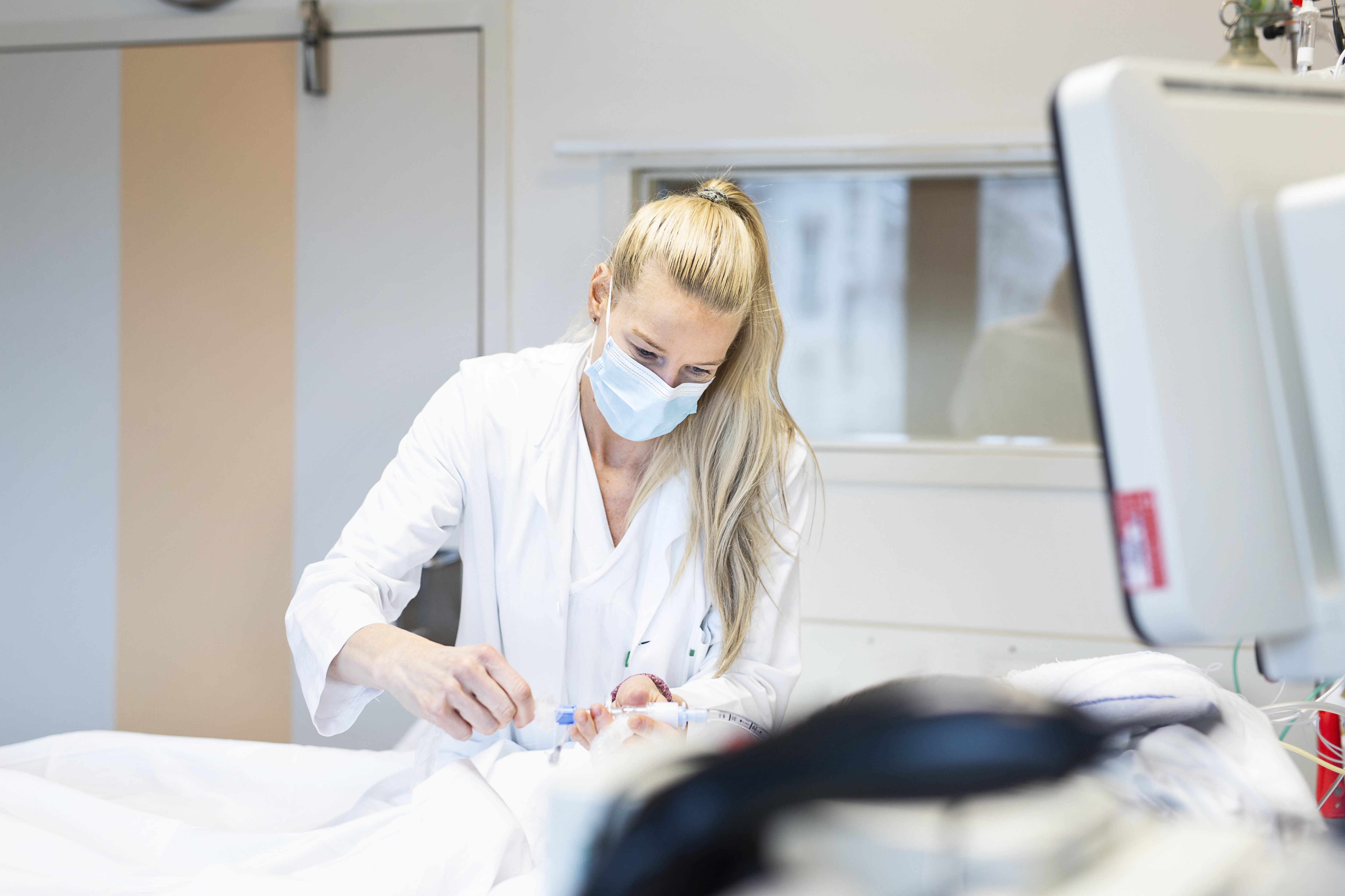 A woman leaning towards a patient in a bed