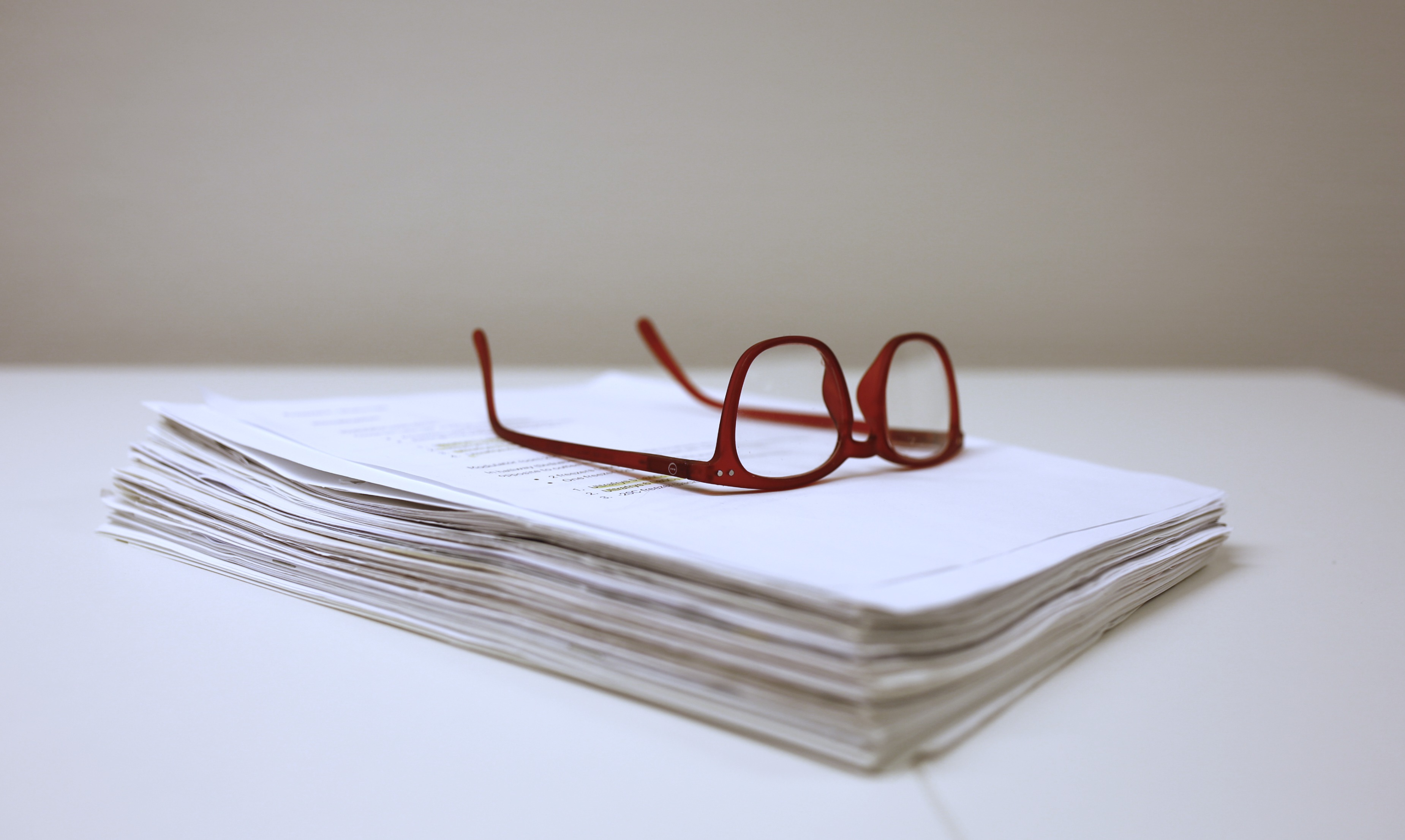 Et par briller på toppen av en bunke papirer