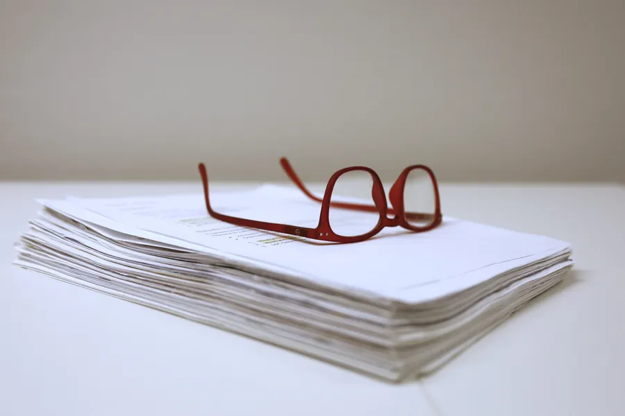 Et par briller på toppen av en bunke papirer