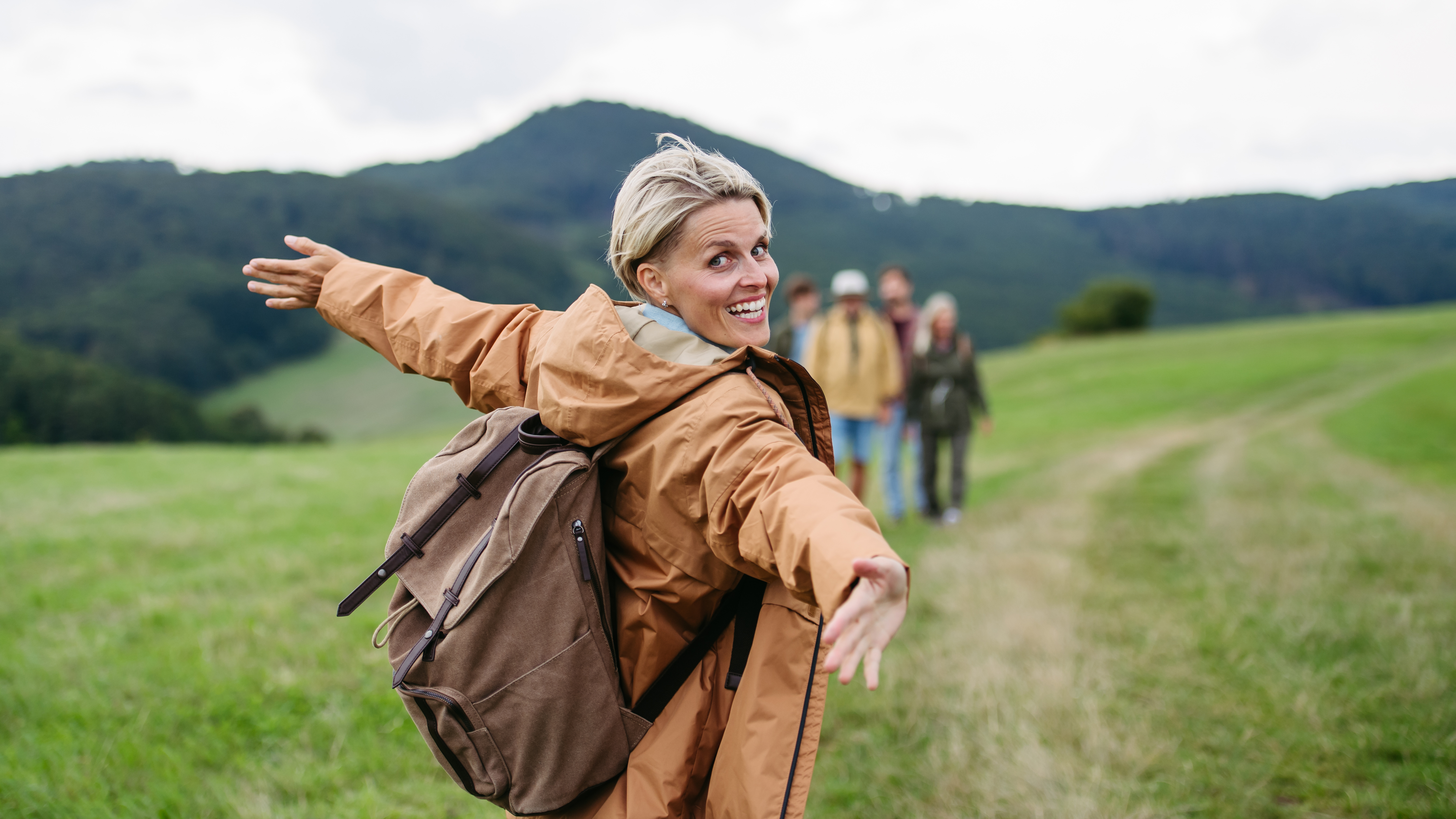 Dame som står på et jorde og strekker ut armene.