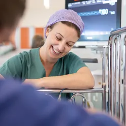 Smilende ansatt ved barneseng_foto