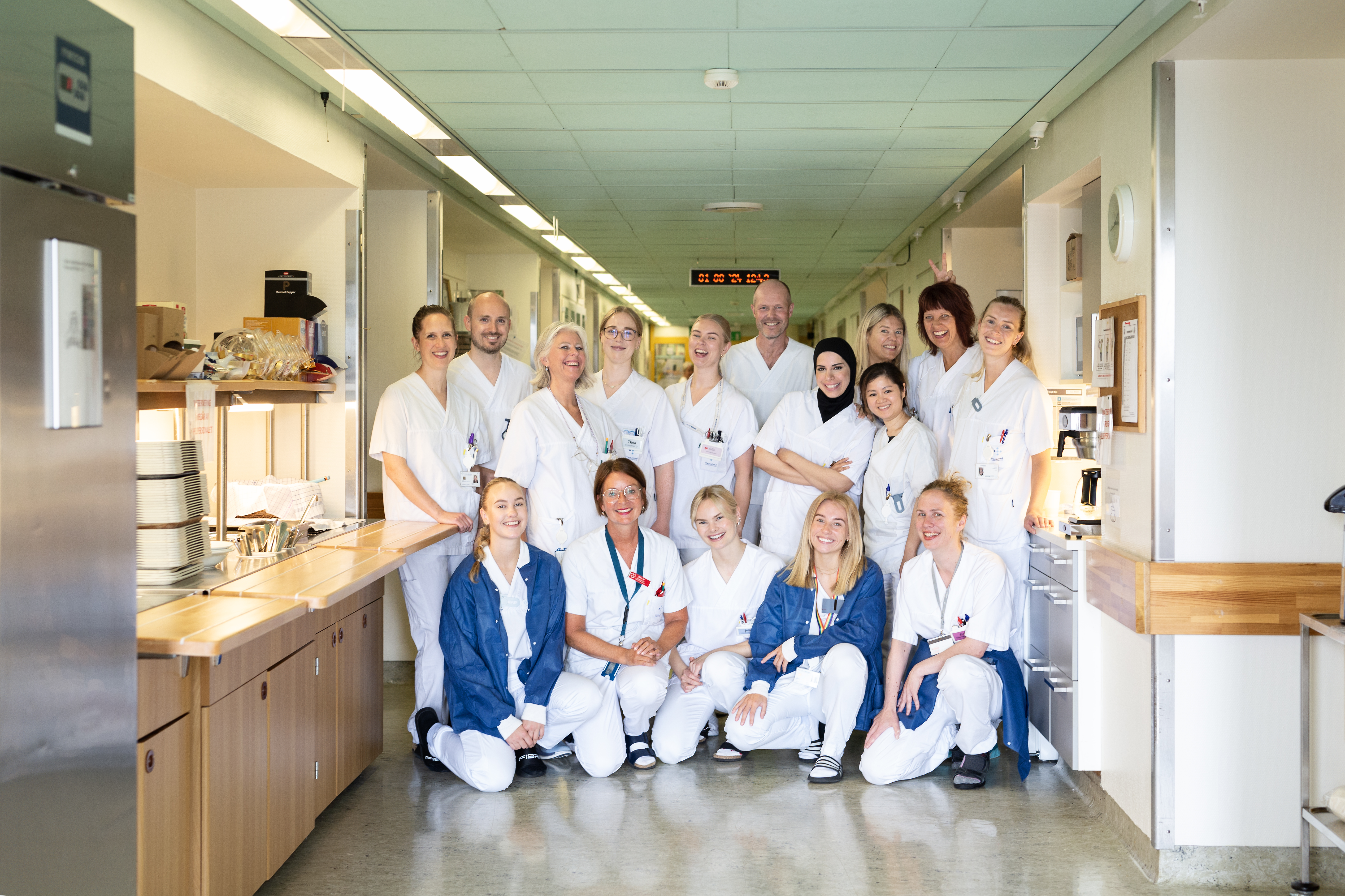 En gruppe kvinner og menn kledd i hvite sykehusuniformer og som står oppstilt for et bilde