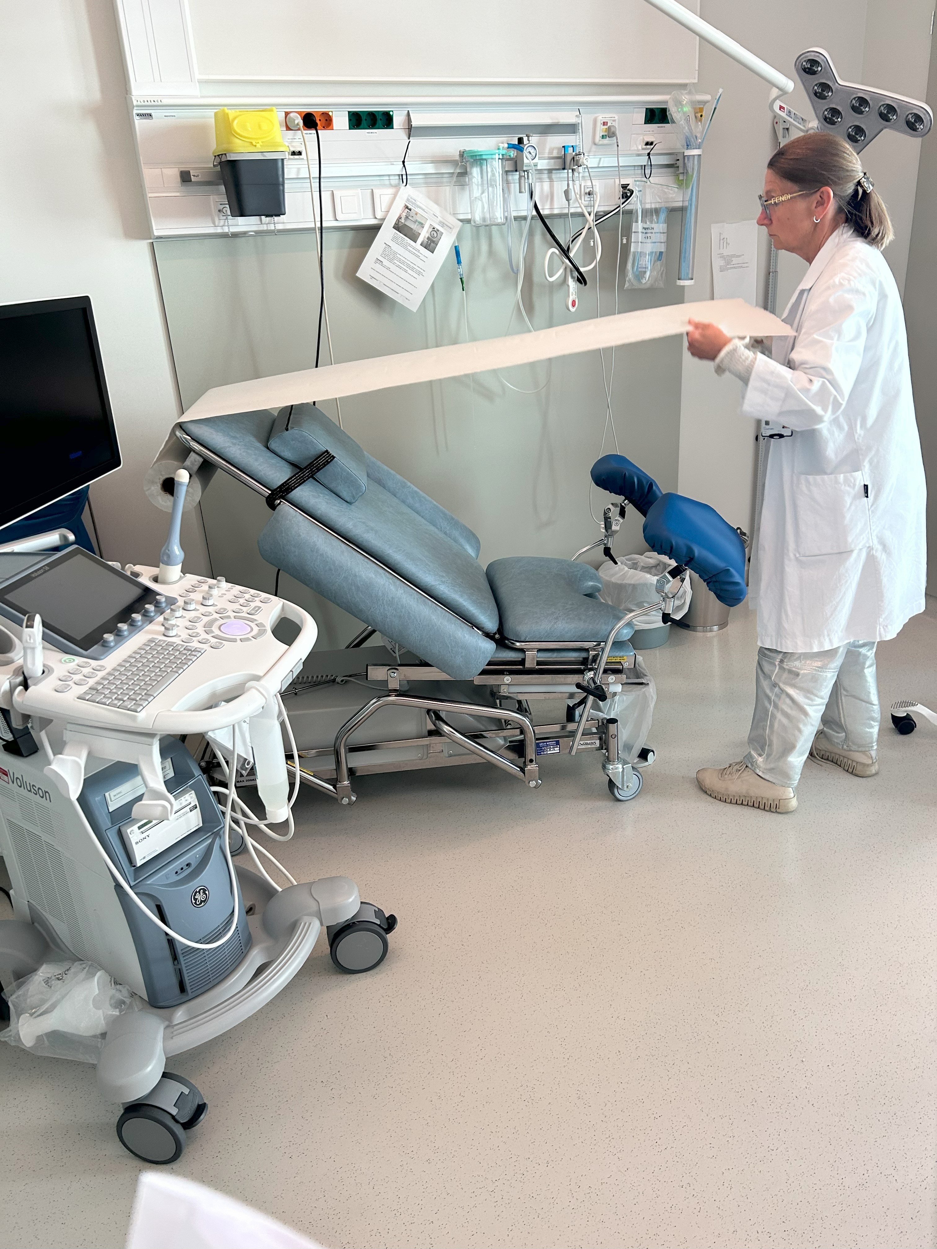 En person i hvit frakk som klargjør en undersøkelsesstol