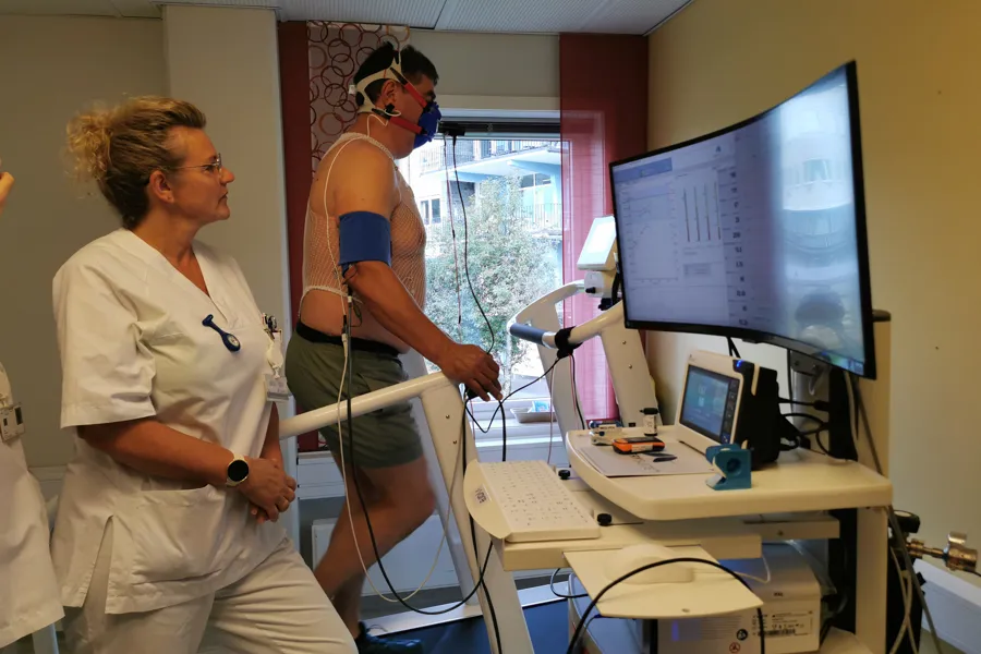 en person på en tredemølle og en person i helseuniform ved siden av