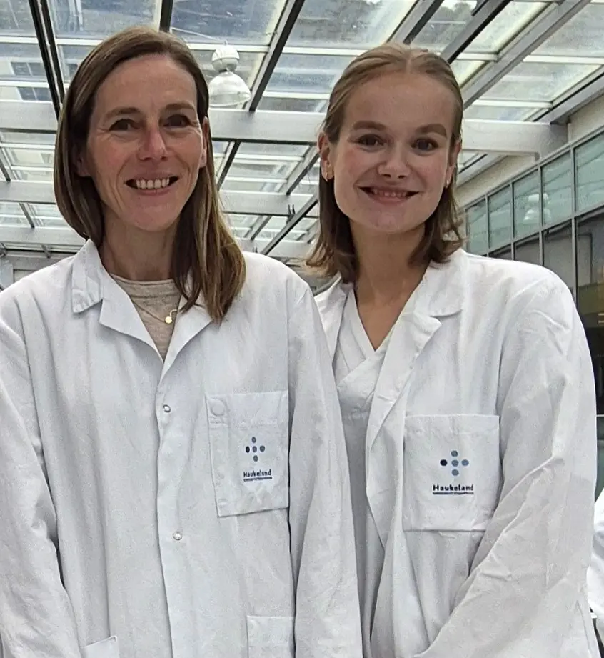 A couple of women wearing white lab coats and badges