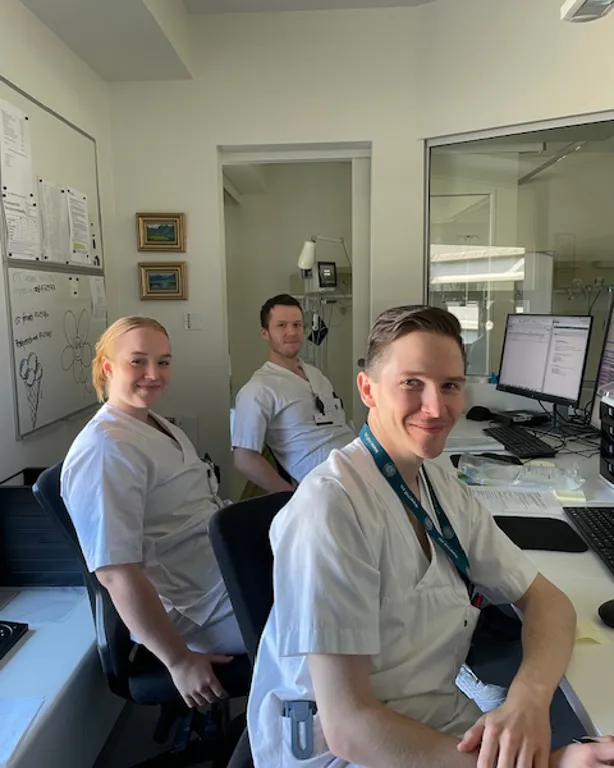 En gruppe mennesker som sitter ved et skrivebord med datamaskiner