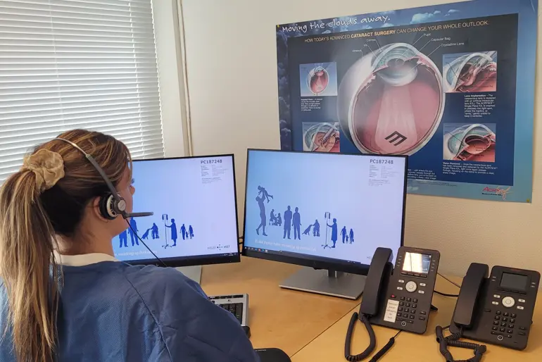 En person med hodetelefoner som sitter ved et skrivebord med en datamaskin