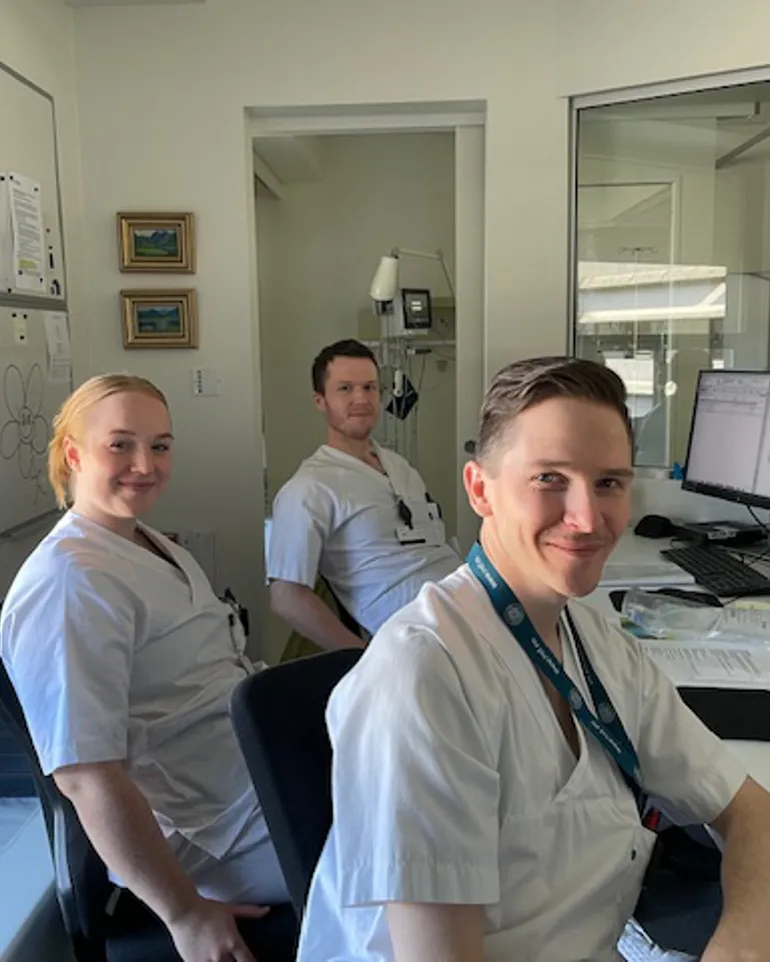 En gruppe mennesker som sitter ved et skrivebord med datamaskiner