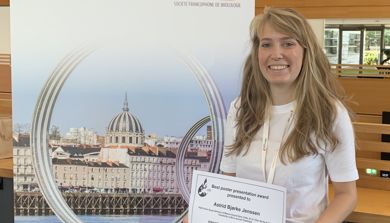 Woman smiling while standing next to roll up  at conference. Photo