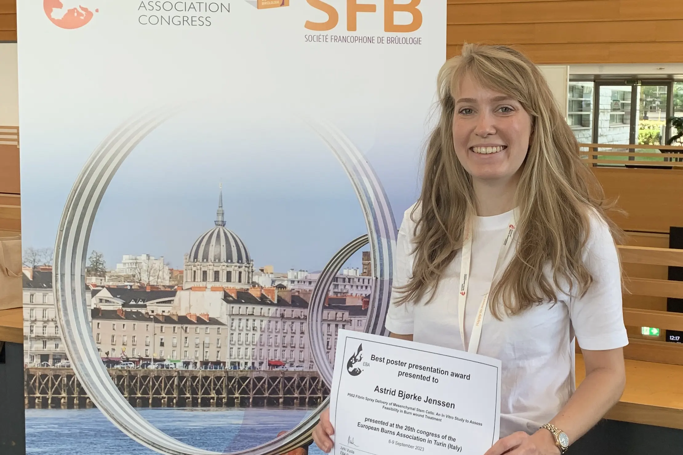 Woman smiling while standing next to roll up at conference. Photo