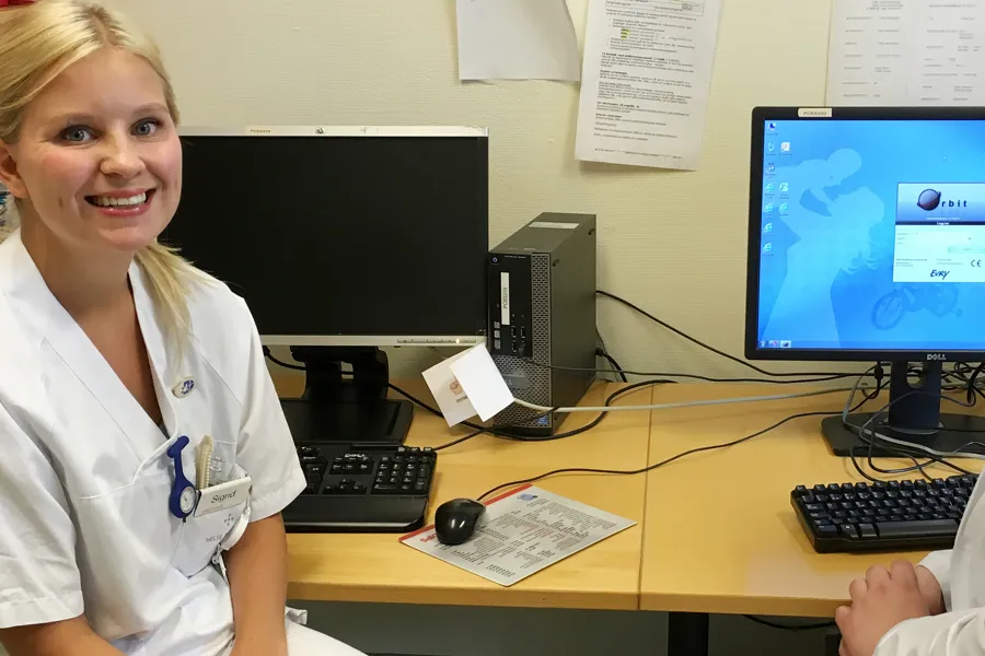 En mann og en kvinne i laboratoriefrakker foran datamaskiner