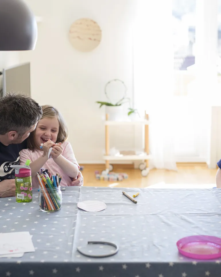 bilde:jente sitter på fanget til far og de snakker med sykepleier