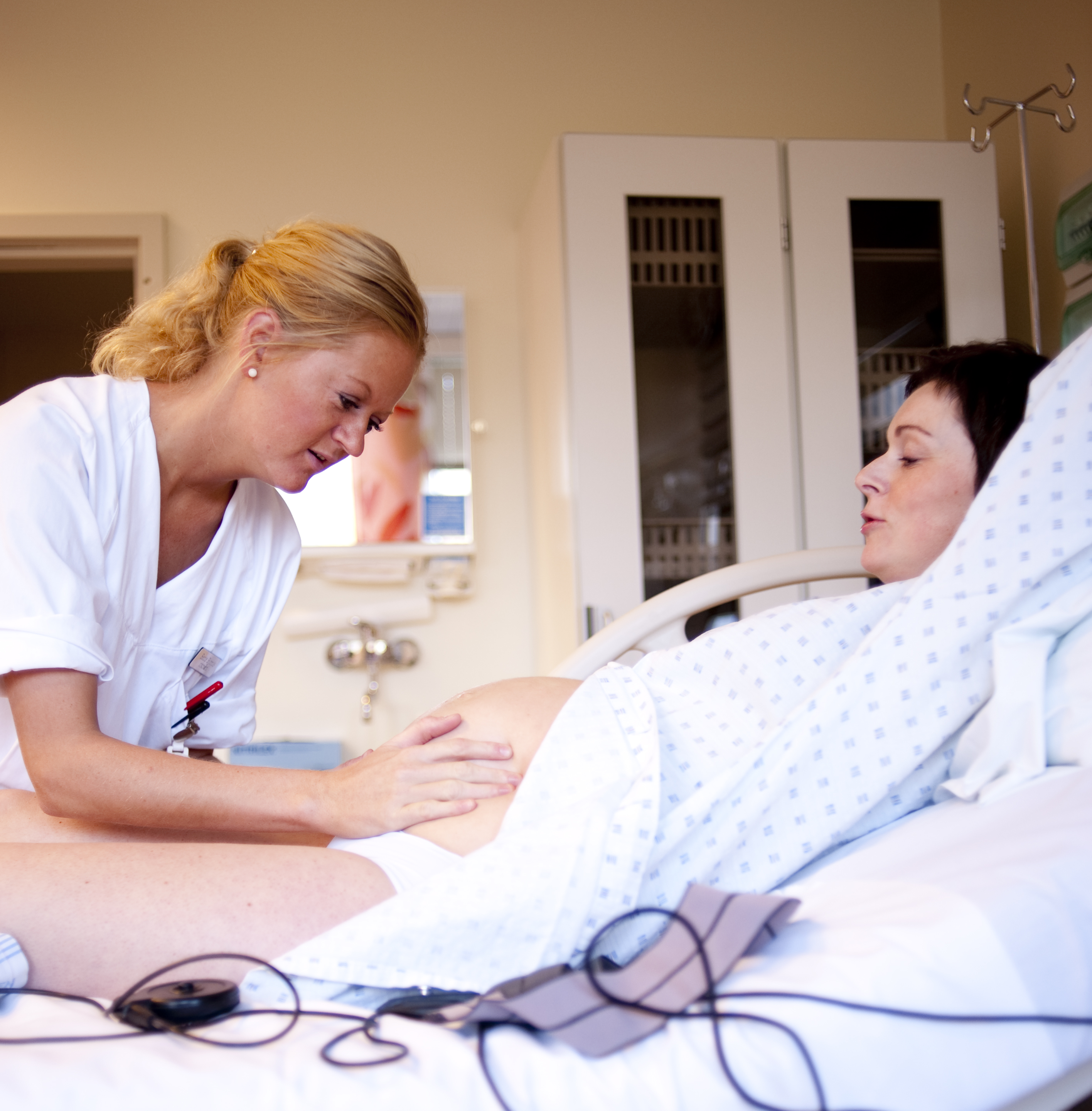 Jordmor undersøker gravid kvinnes mage. Foto