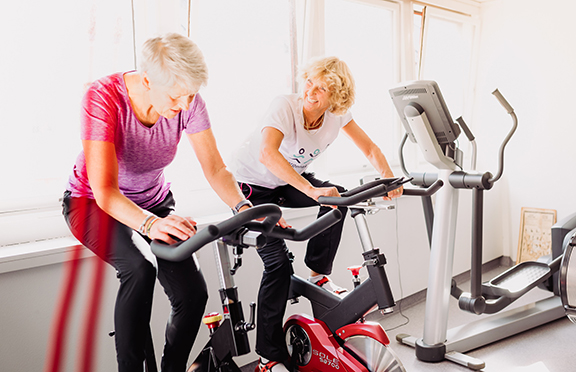 To damer trener på ergometersykkel