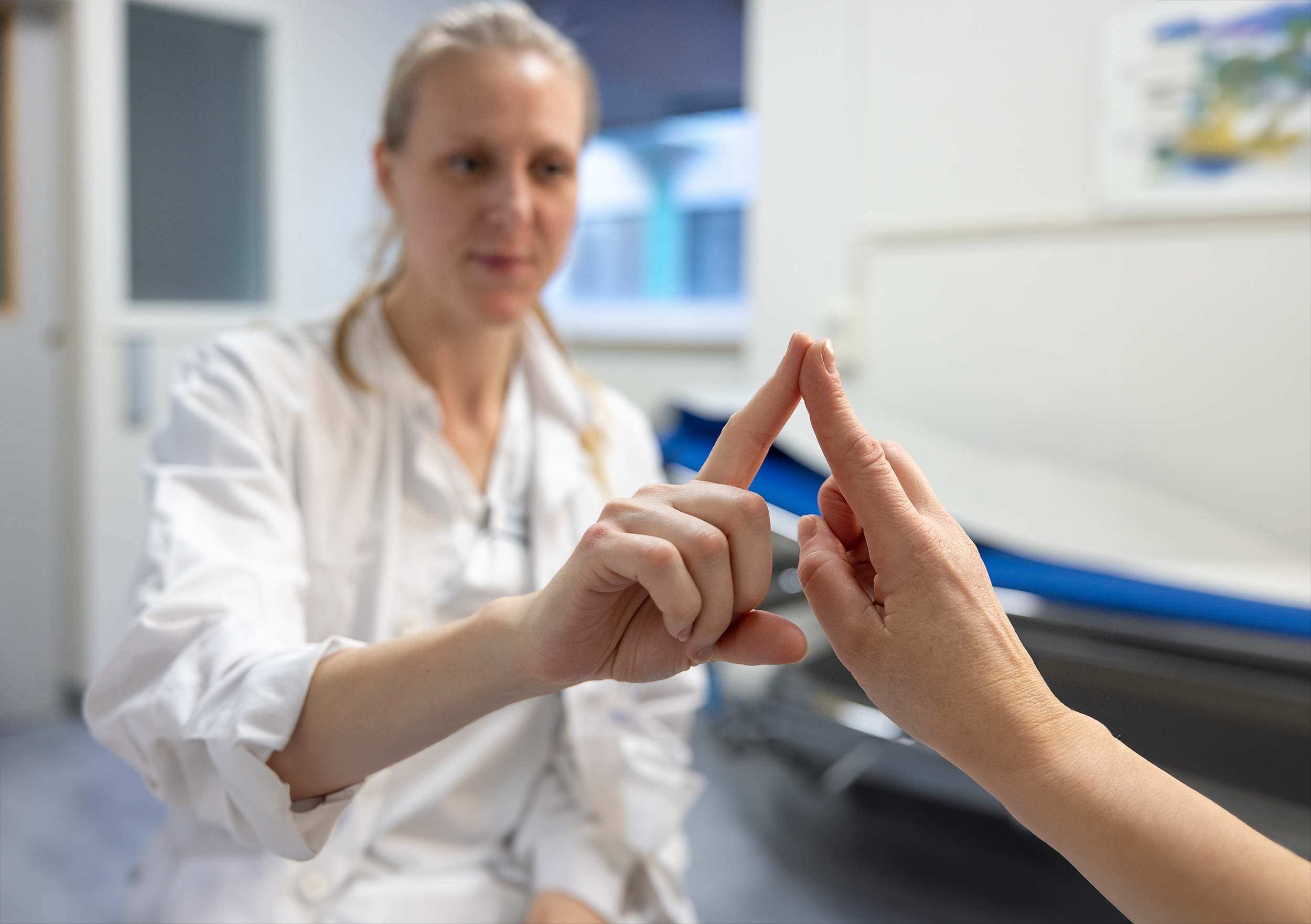 Testing for Parkinsons: en sykepleier holder opp pekefingeren og ber pasienten om å holde sin pekefinger opp stødig på samme måte