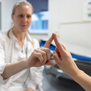 Testing for Parkinsons: en sykepleier holder opp pekefingeren og ber pasienten om å holde sin pekefinger opp stødig på samme måte