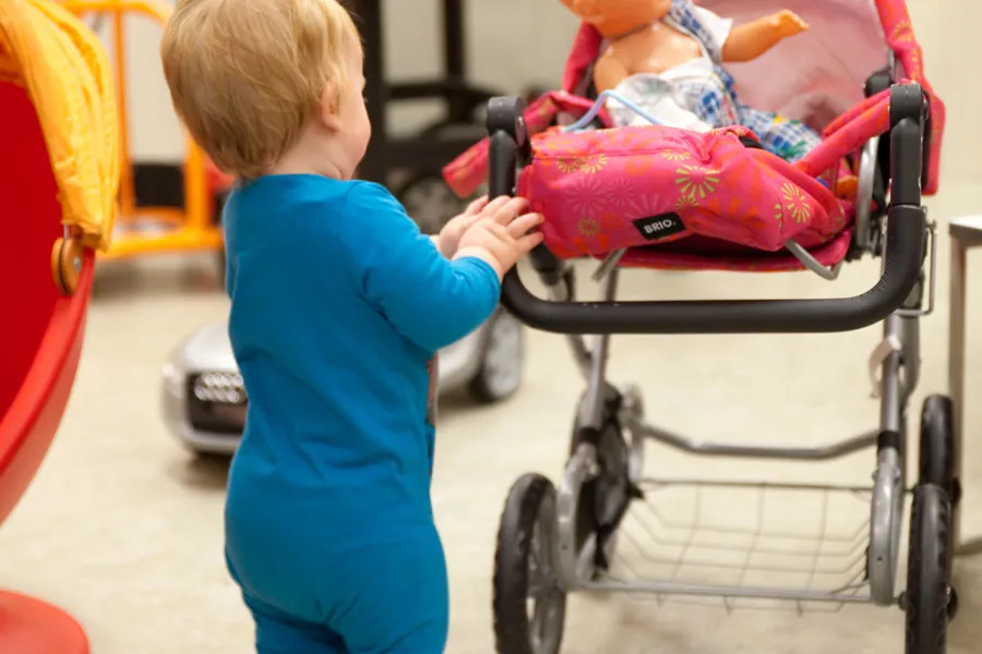 Foto. Et barn som kjører en dukkevogn
