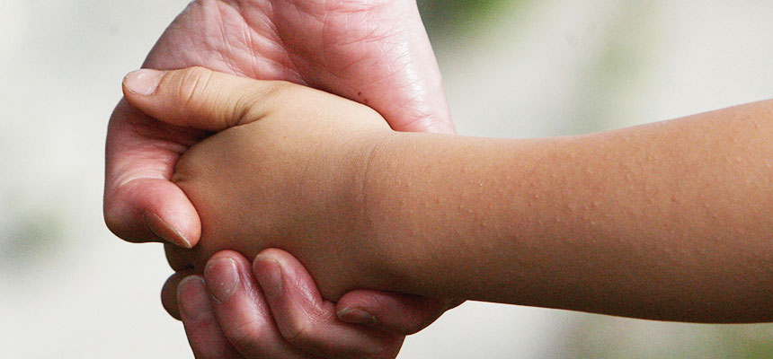 Barnehånd held vaksenhand. Foto