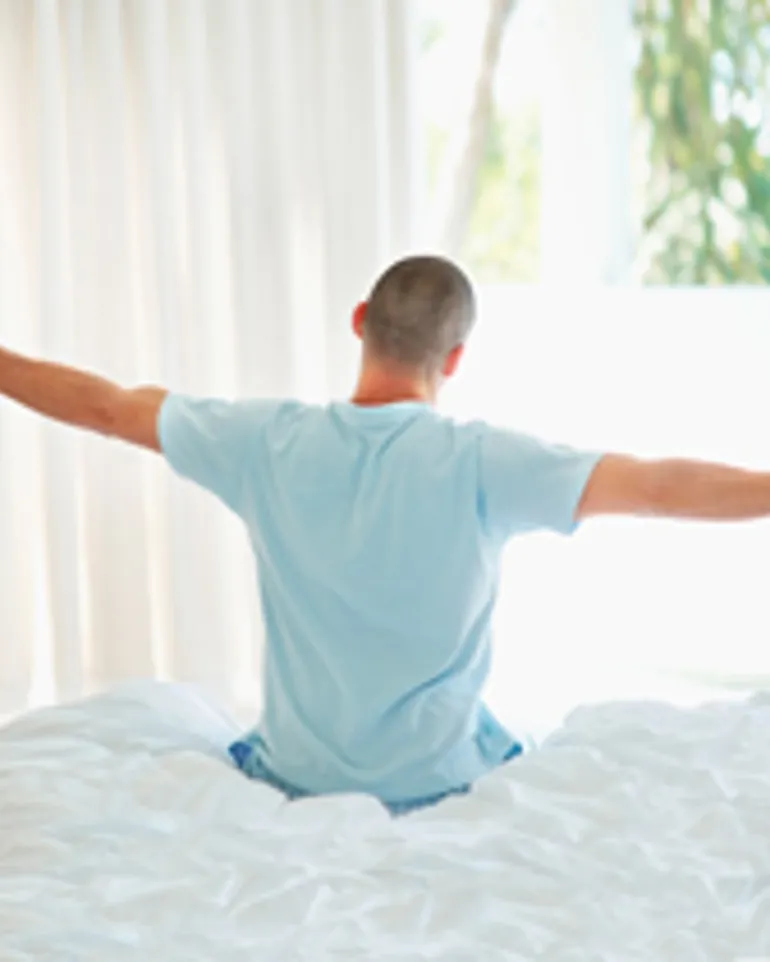 Foto: mann strekker ut armene i sengen