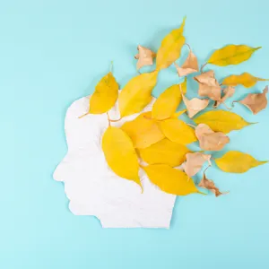 Illustrasjon med papirklipp av et hode med høstløv som blåser ut av hodet.