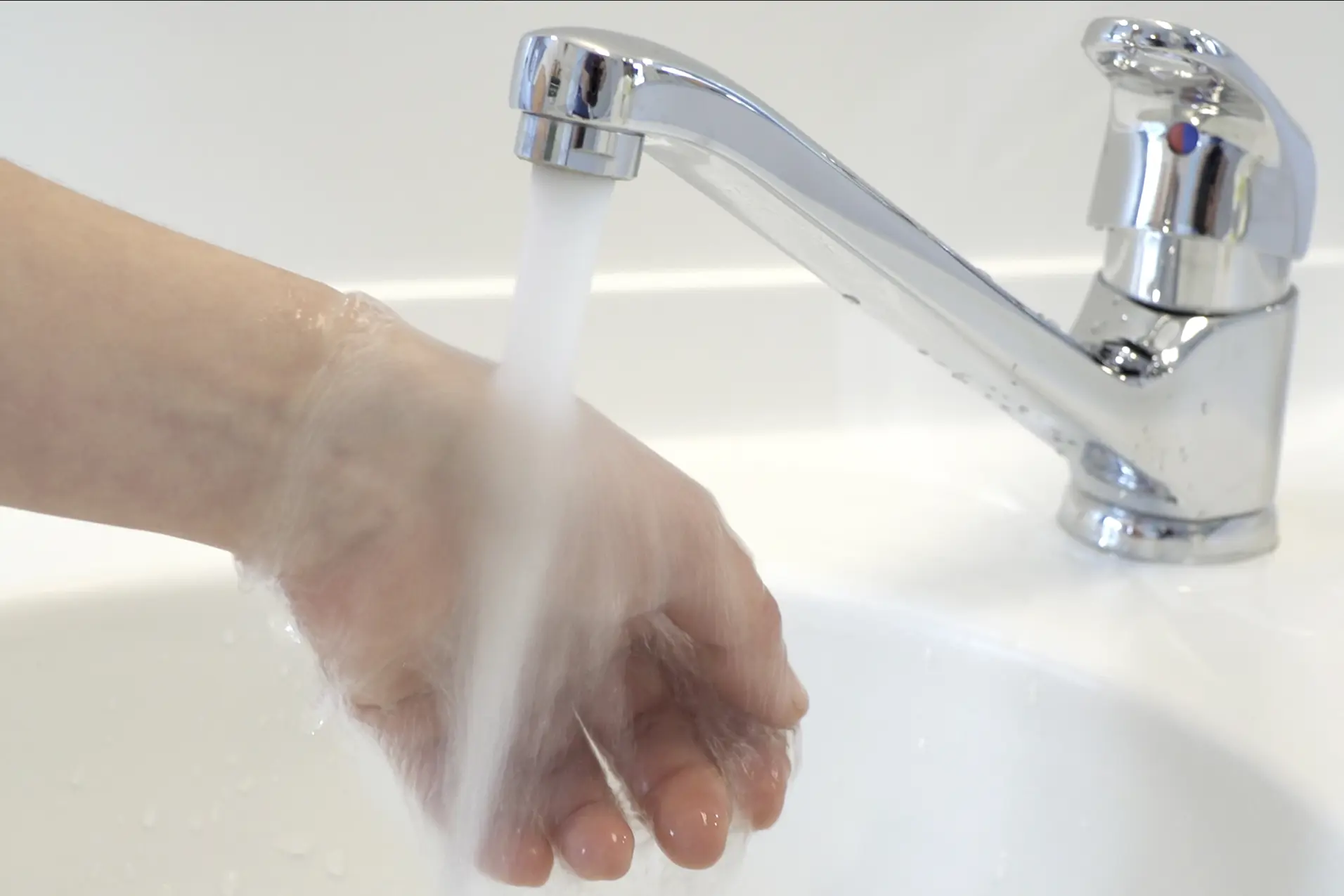 En hånd under rennende vann i springen