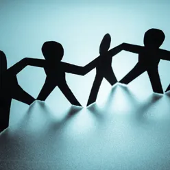 Papirmenneskefigurer i svart på rekke mot blå bakgrunn. Illustrasjonsfoto