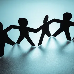 Papirmenneskefigurer i svart på rekke mot blå bakgrunn. Illustrasjonsfoto