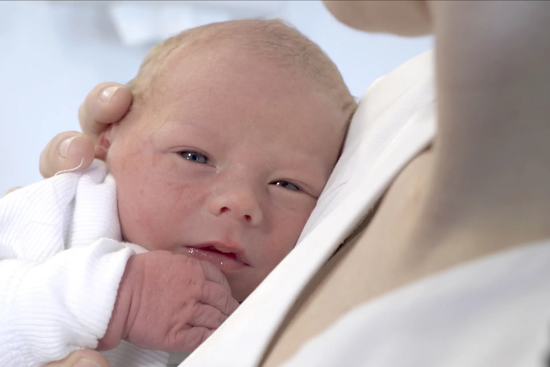 En baby ligger på brystet til en person