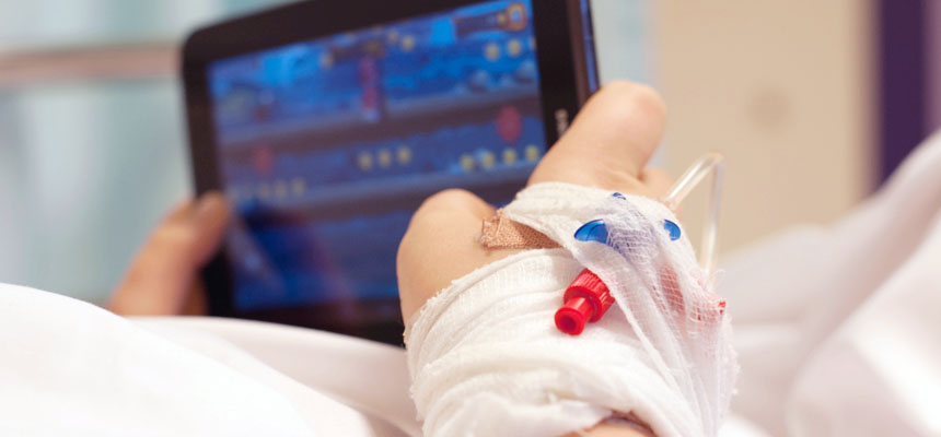 Holder nettbrett med venflon på hånden. Foto