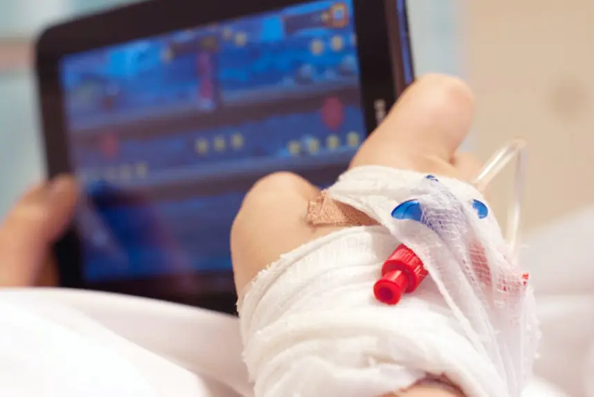 Holder nettbrett med venflon på hånden. Foto