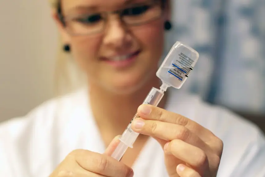 Sykepleier trekker opp saltvann i en sprøyte. Foto