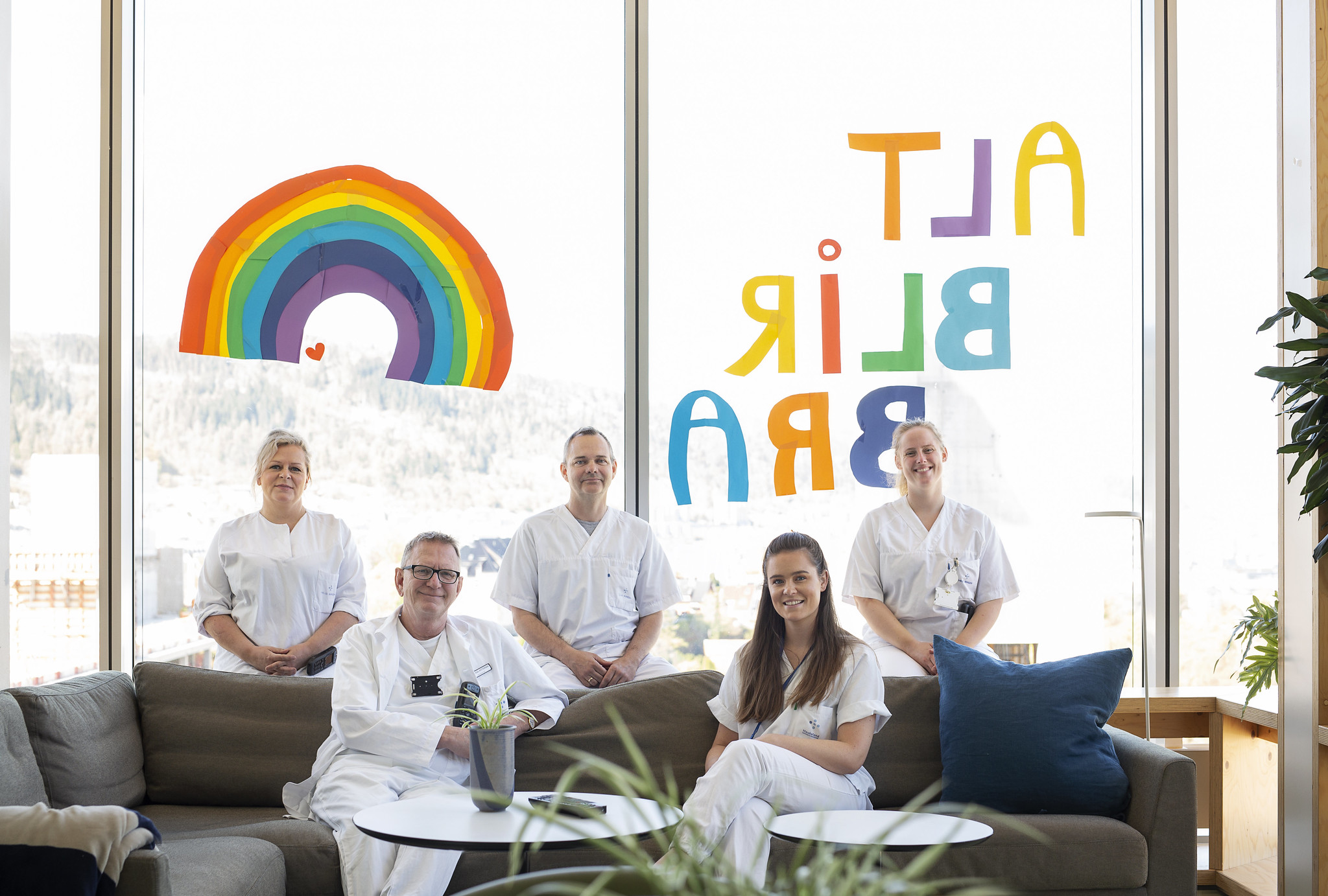 Helsepersonell sitter i sofa foran vindu med utsikt. Foto