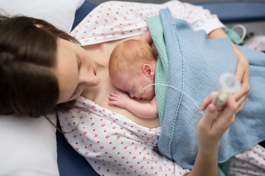 Prematurt barn på mors bryst. Foto