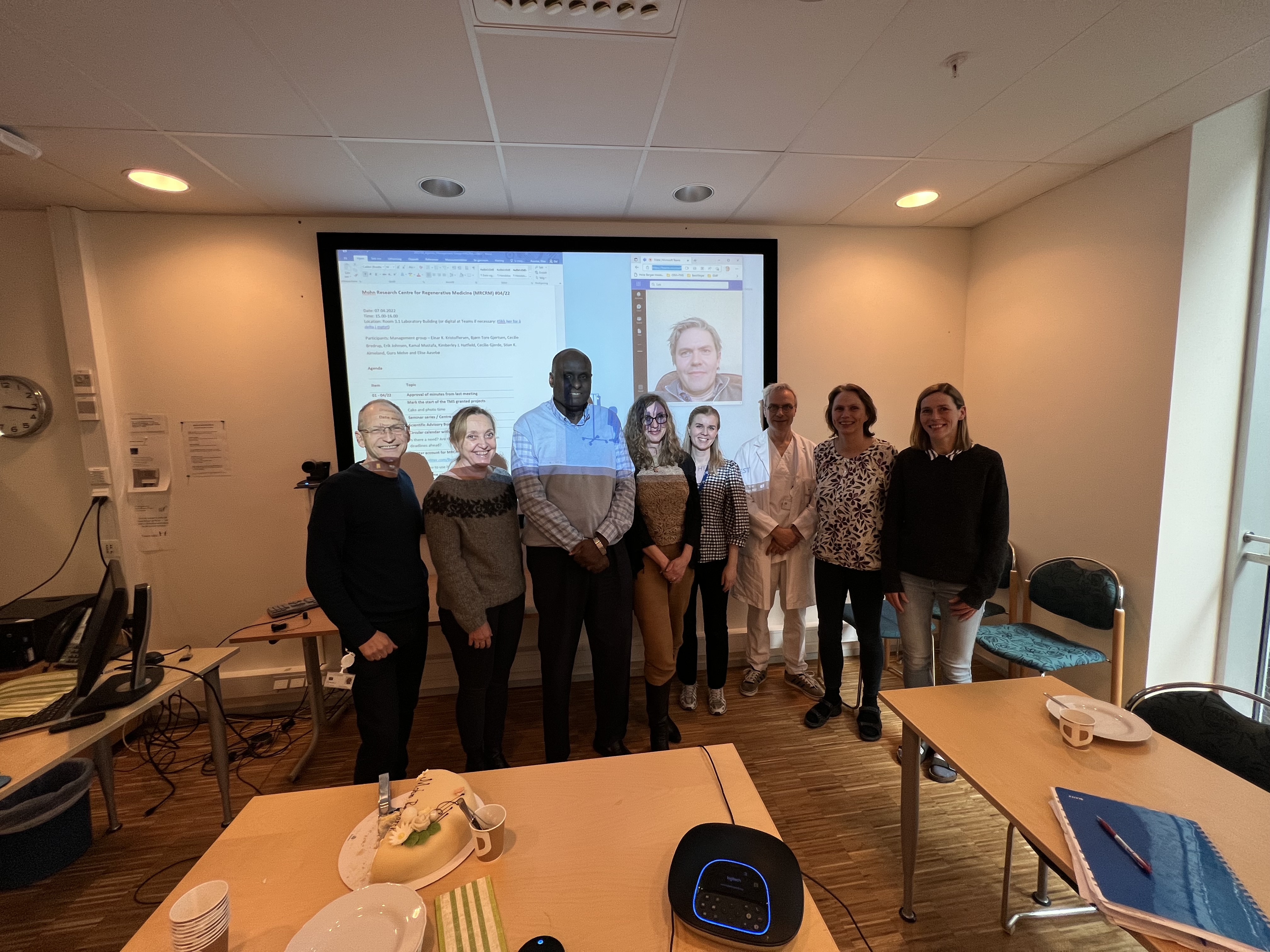 En gruppe mennesker som står foran en projektorskjerm