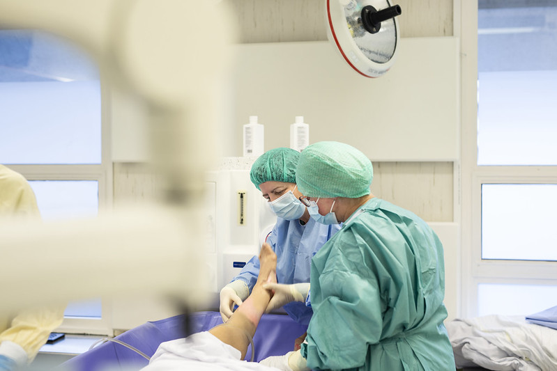 Helsepersonell iført smittevernutstyr behandler pasient. Foto