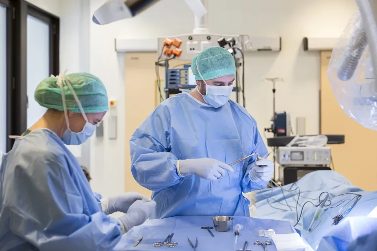 Operasjonssykepleier og kirurg på operasjonssal. Foto