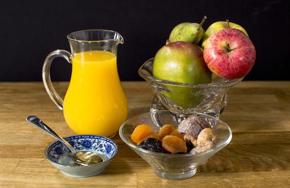 En mugge med uice ved siden av en bolle med frukt