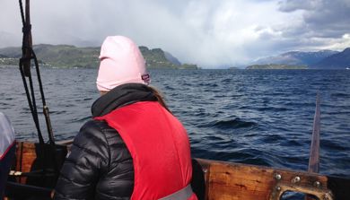 Foto. Person i båt ser ut mot havet.
