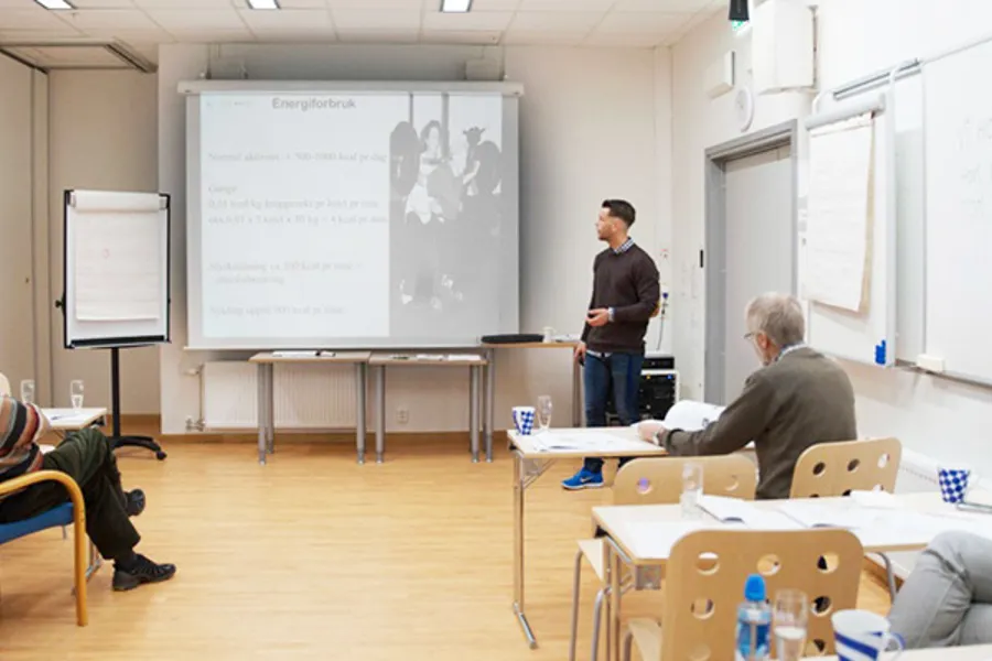 Kursholder foreleser med presentasjon på lerret i lokale med flere kursdeltakere i klasseromsetting. Foto