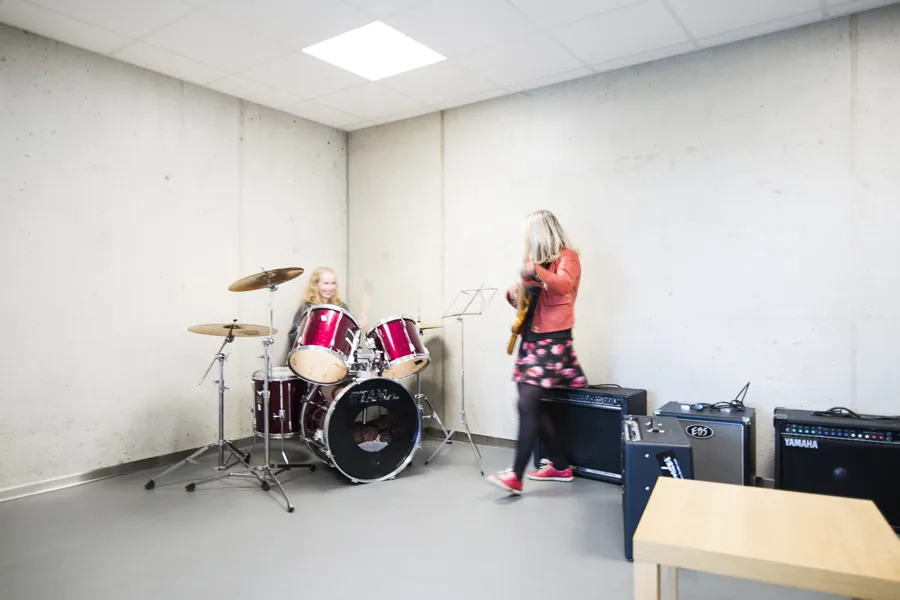 Bilde av to damer. En på trommer og en på gitar.