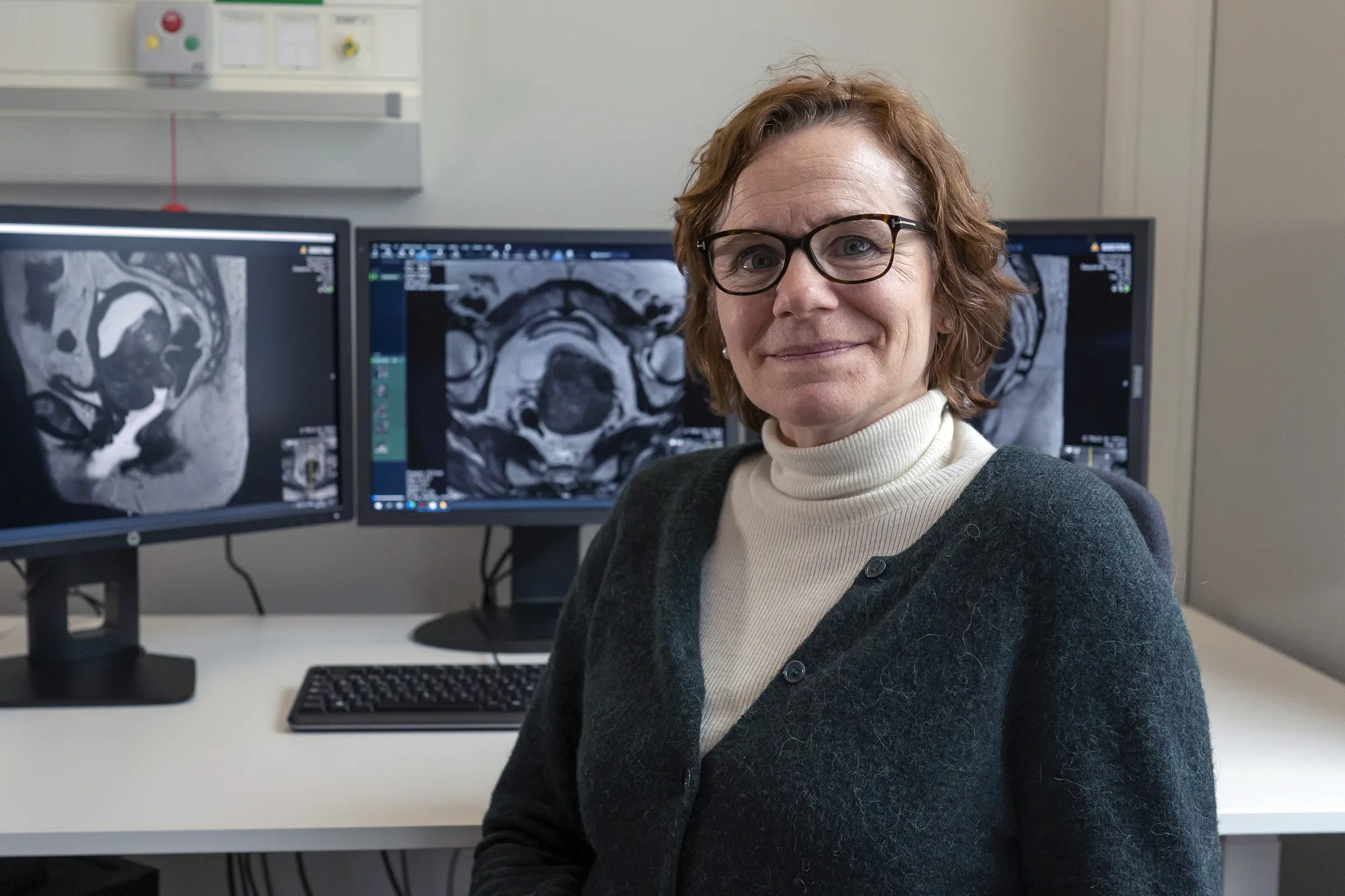 Ingfrid Haldorsen foran tre dataskjermer med MR-bilder. Foto