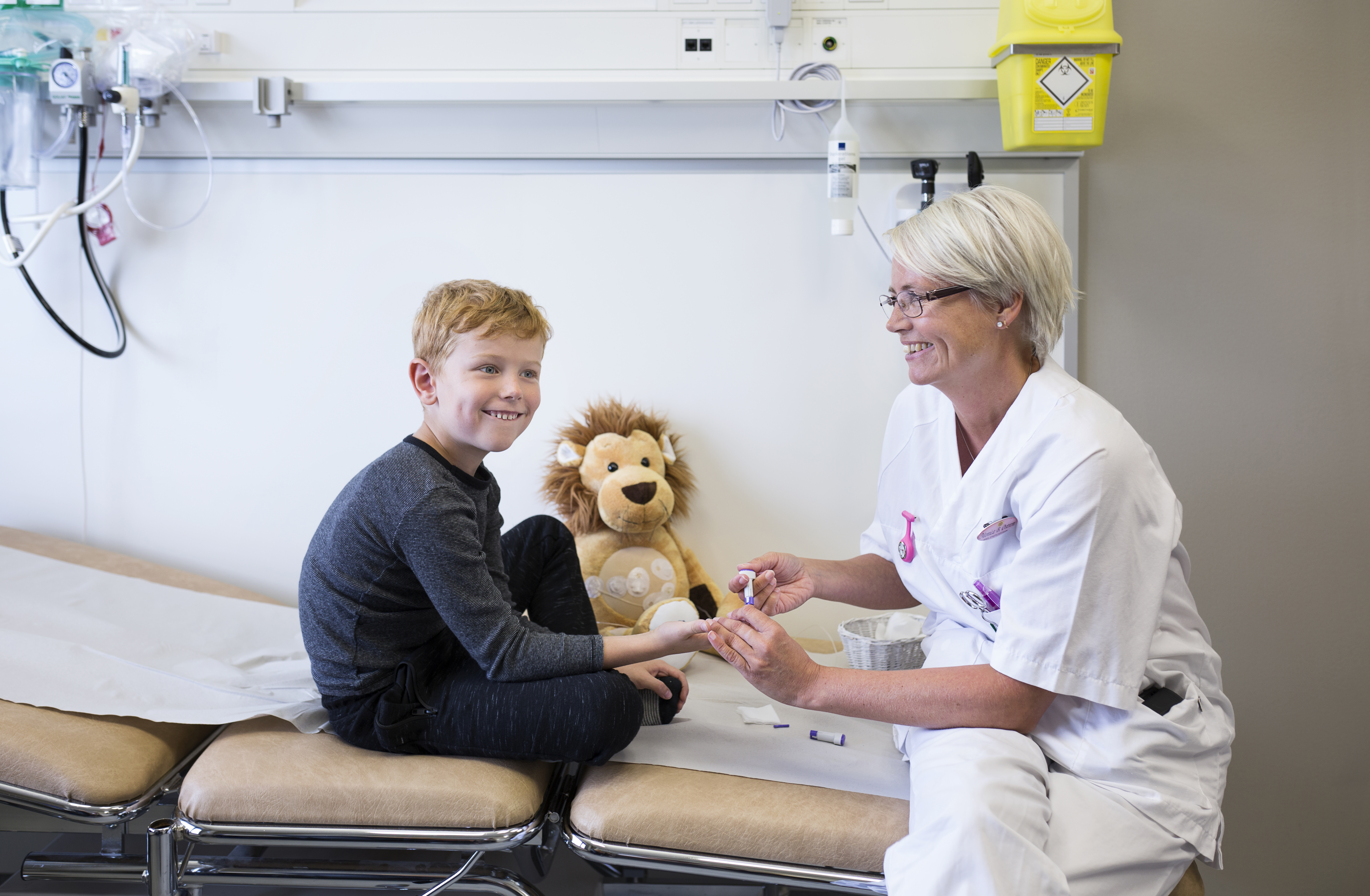 Gutt på undersøkingsbenk og sjukepleiar. Foto