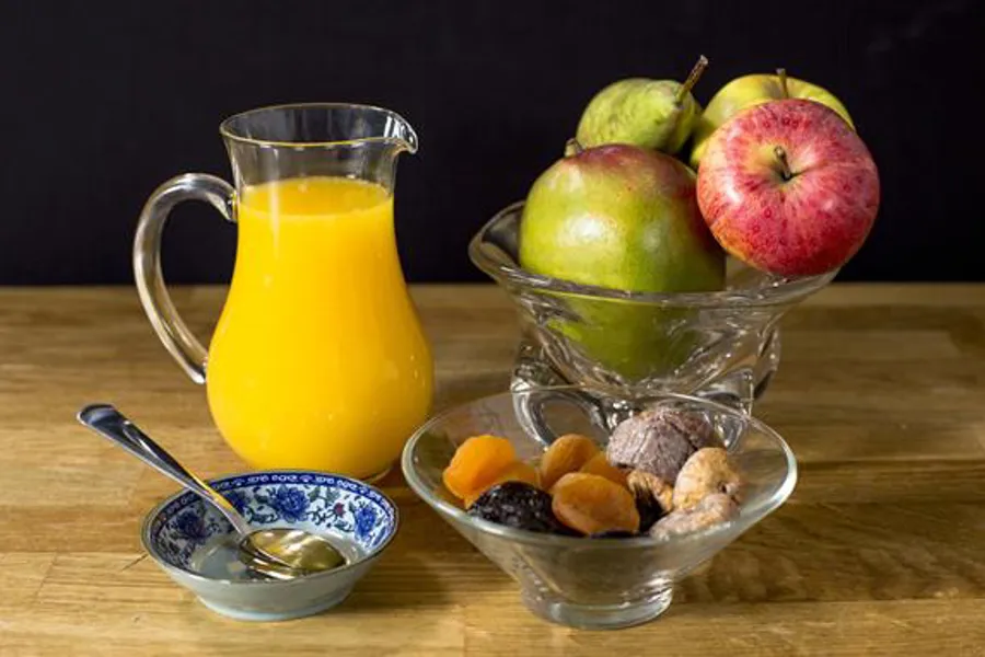 Et glass juice ved siden av en bolle med frukt