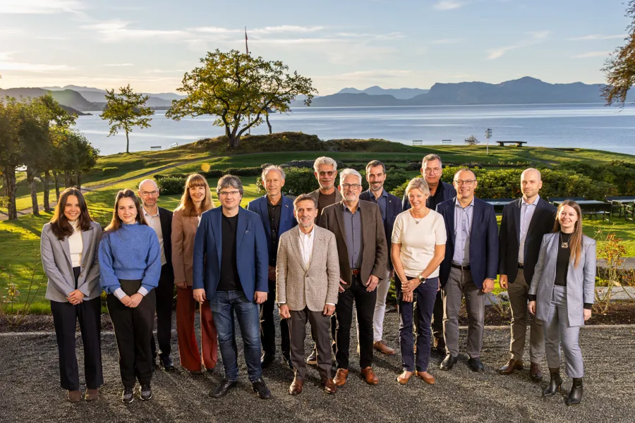 The speakers of the symposium, 15 people, posing with the fjord in the background.