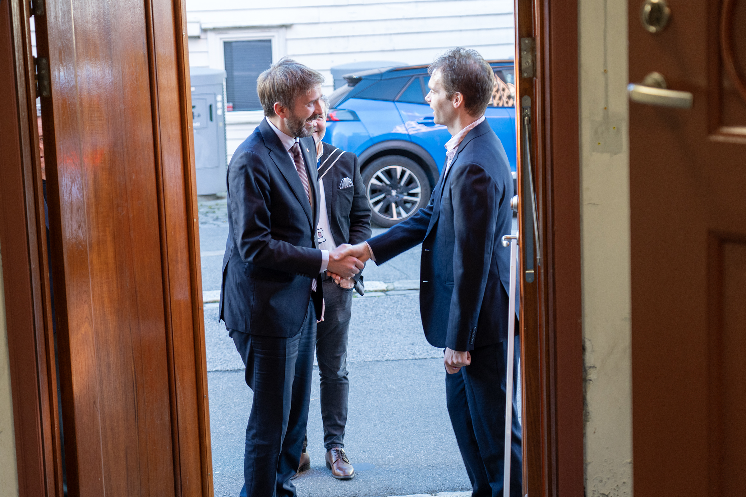 Et par menn i dress som går inn i en bygning