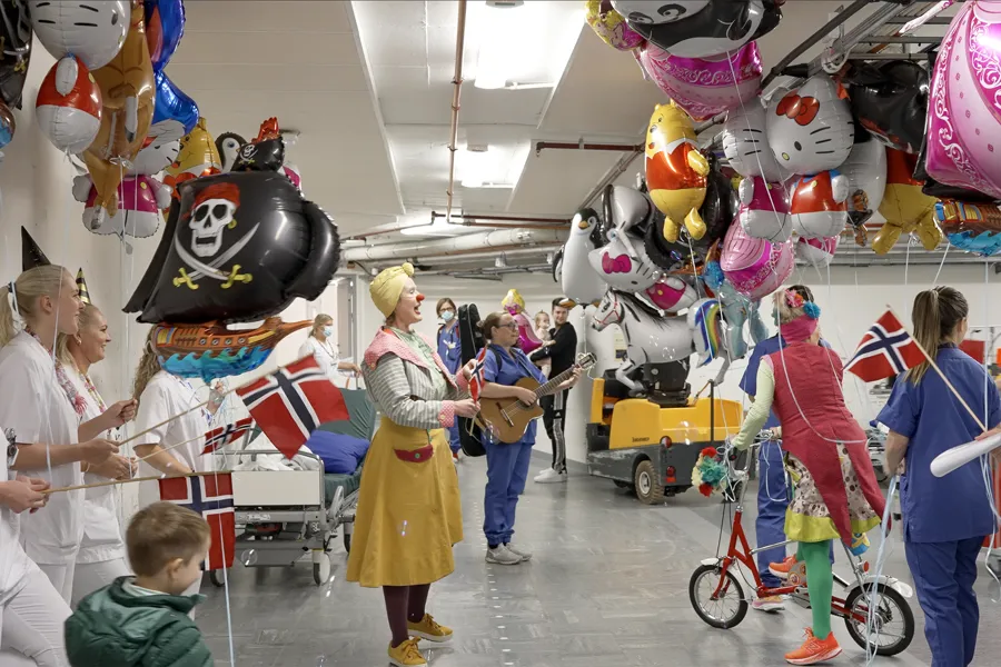 Flere barn og voksne går i tog med ballonger og flagg