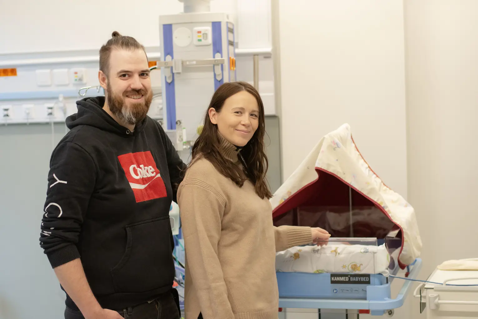 En mann og kvinne ved siden av en baby på nyfødtintensiv