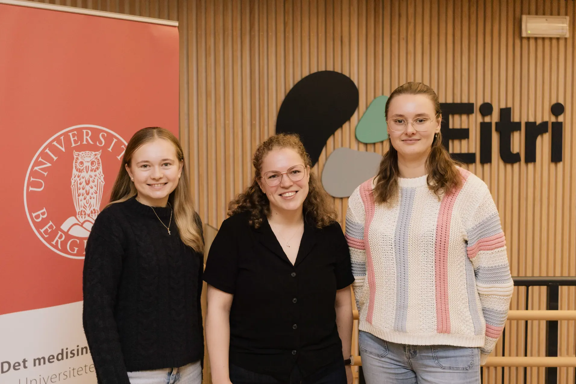 tre unge damer står og smiler